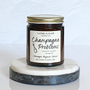 A jar candle with a label reading 'Champagne Problems' and topped with multi-colored eco-glitter, sitting on a marble surface.