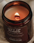 Candle labeled 'City of Roses' by 'Flame' on a textured surface.