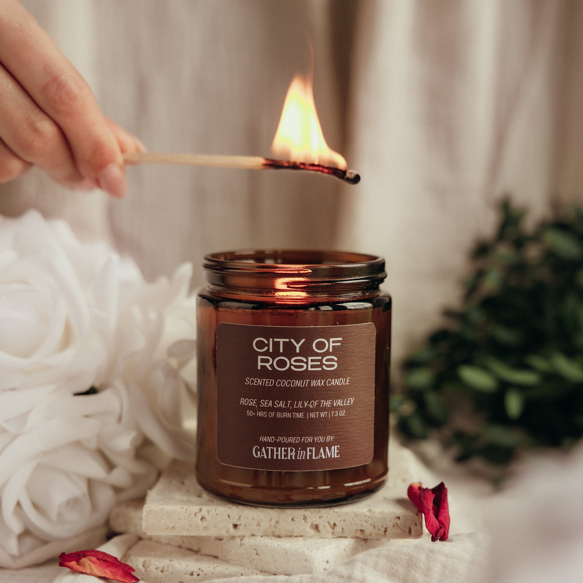 Candle labeled 'City of Roses' being lit with a match, surrounded by flowers and decorative elements.