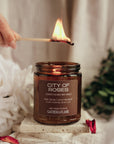 Candle labeled 'City of Roses' being lit with a match, surrounded by flowers and decorative elements.