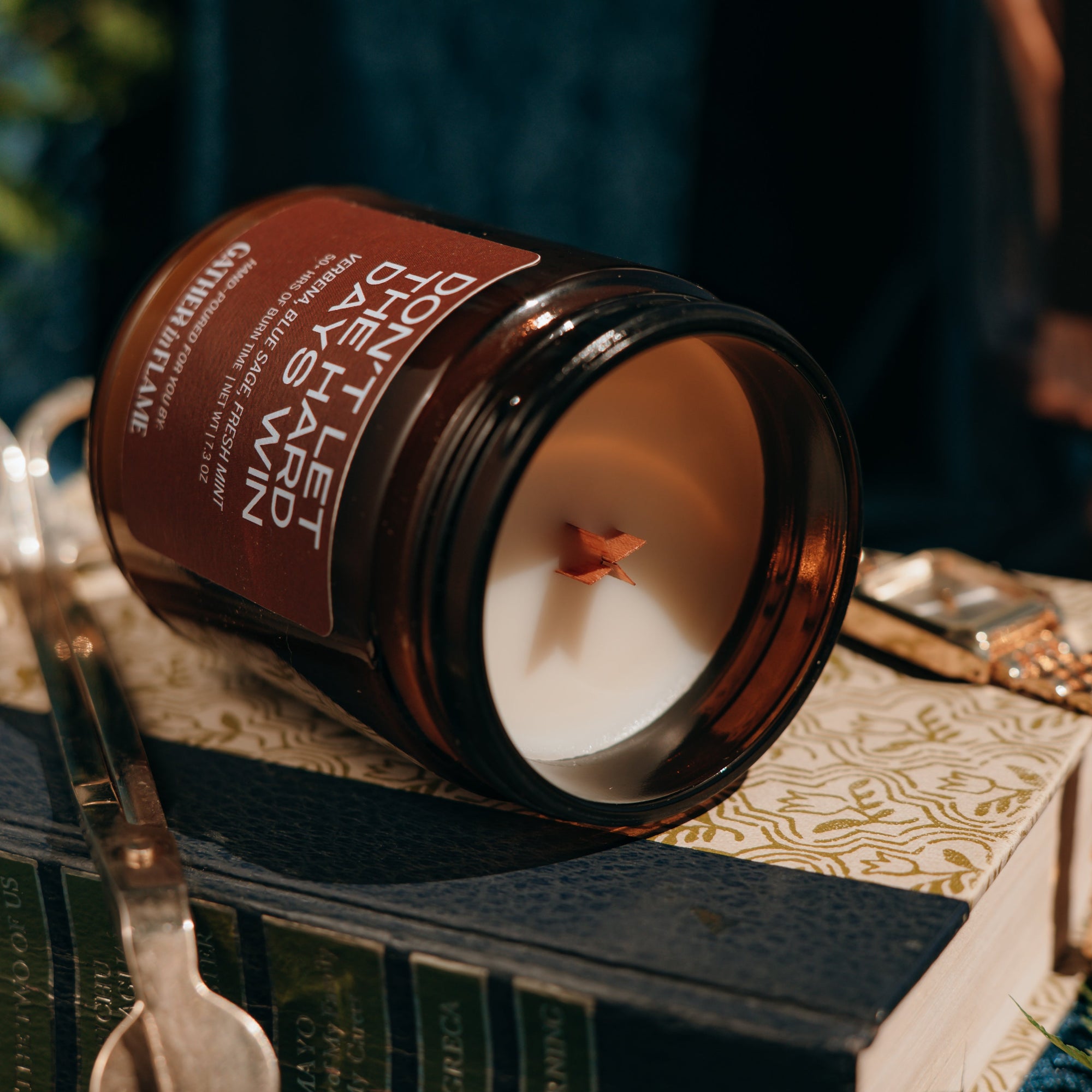 Candle in an amber jar on top of a book with a dark background