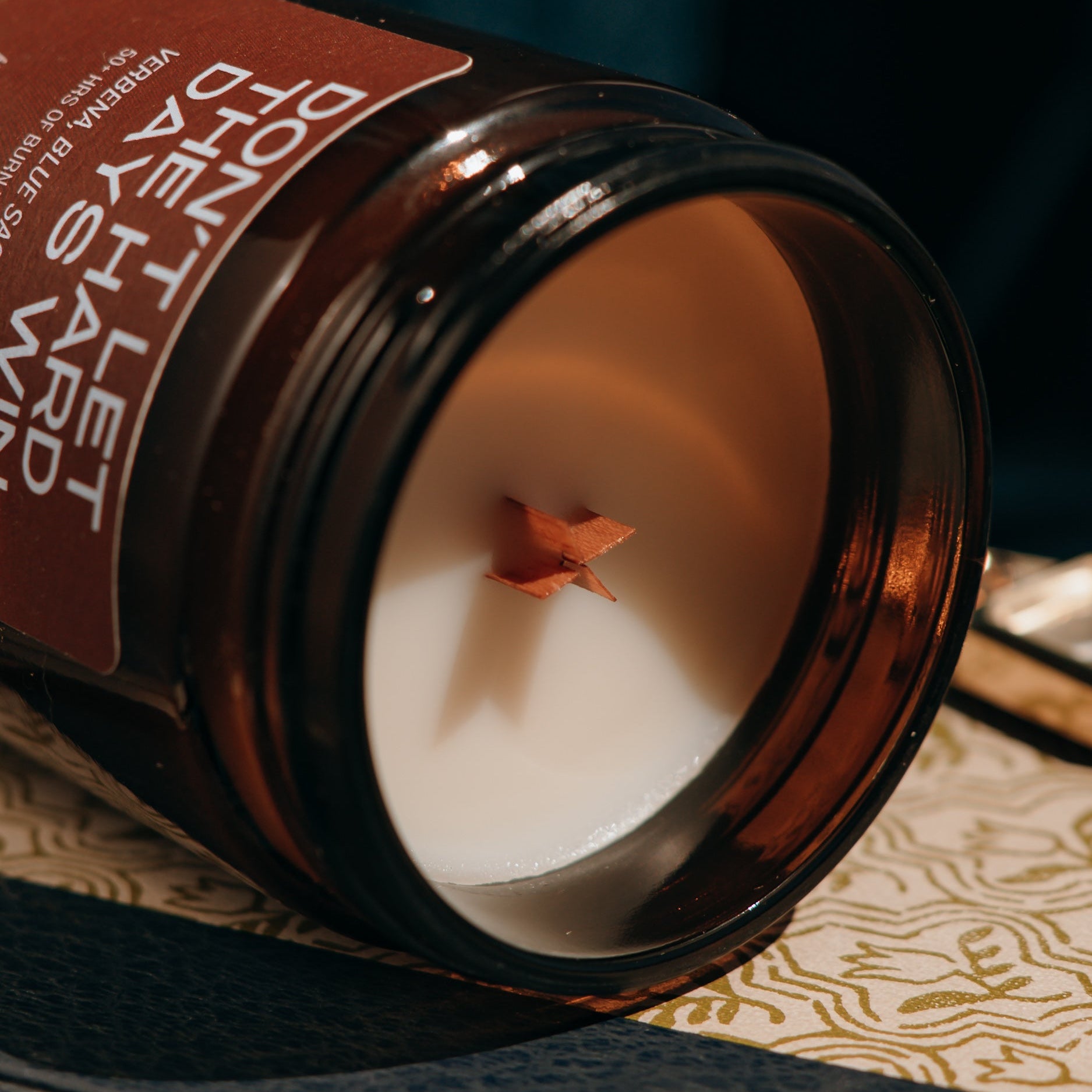 Candle in an amber jar with a decorative label on a textured surface