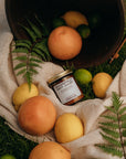 Jar of jam on a blanket with fruits and a bucket in a natural setting