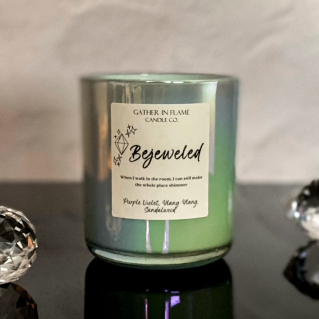 Large blue iridescent candle jar with large label reading Bejeweled with crystals in the foreground