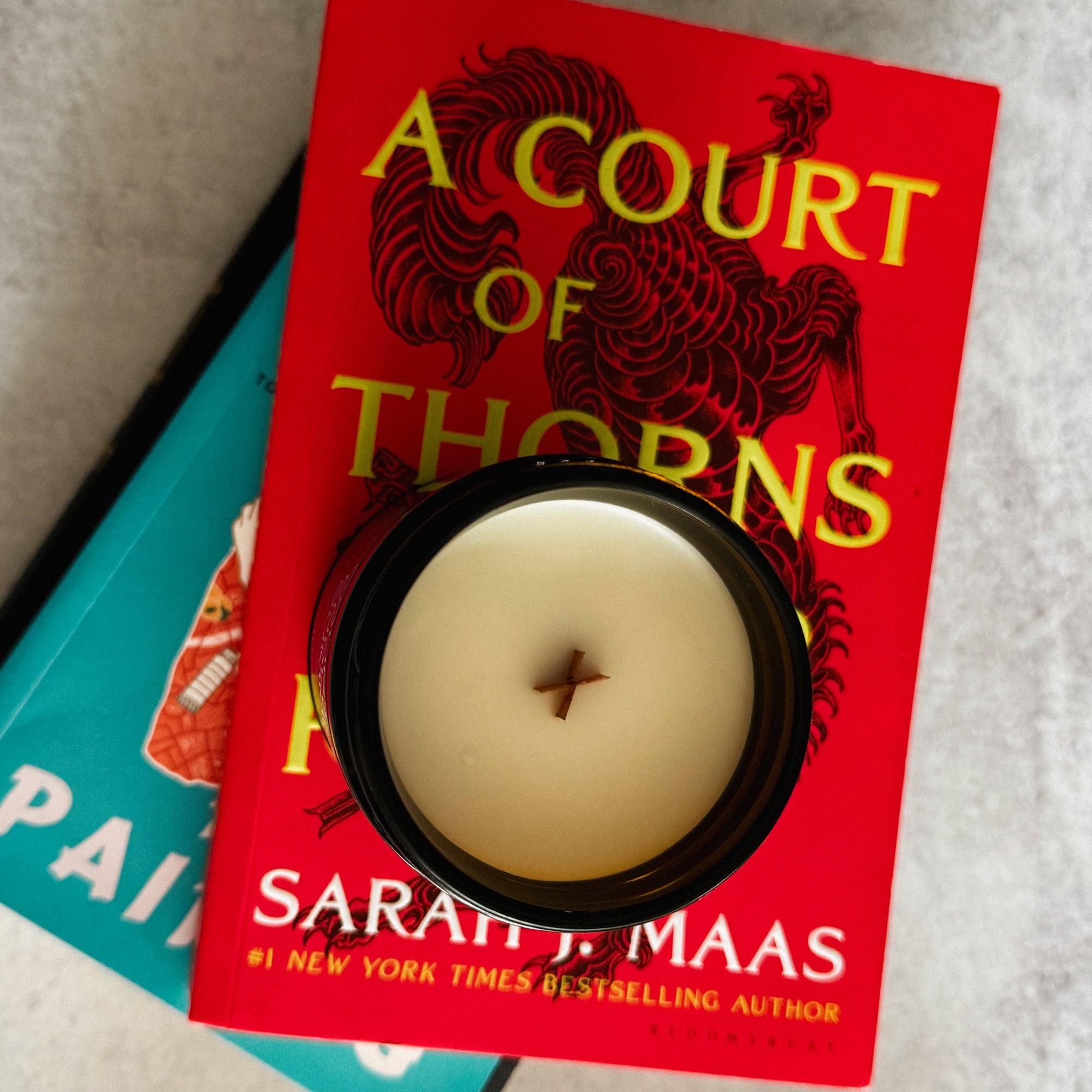 Book titled 'A Court of Thorns' by Sarah J. Maas with a candle on top