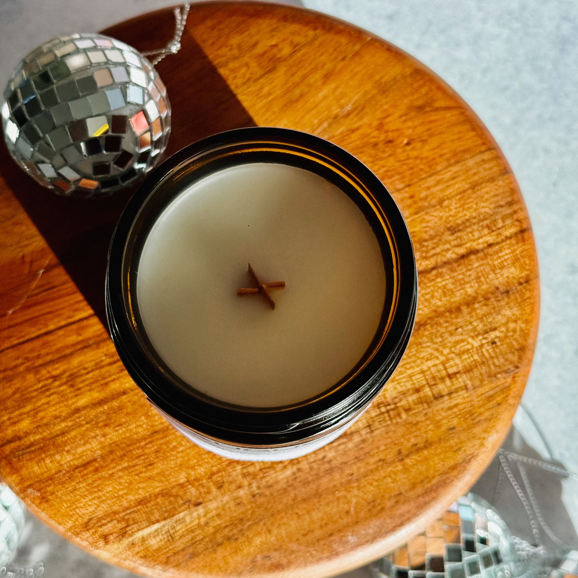 Candle in a black holder on a wooden surface with disco balls in the background