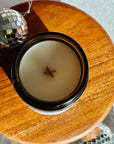 Candle in a black holder on a wooden surface with disco balls in the background