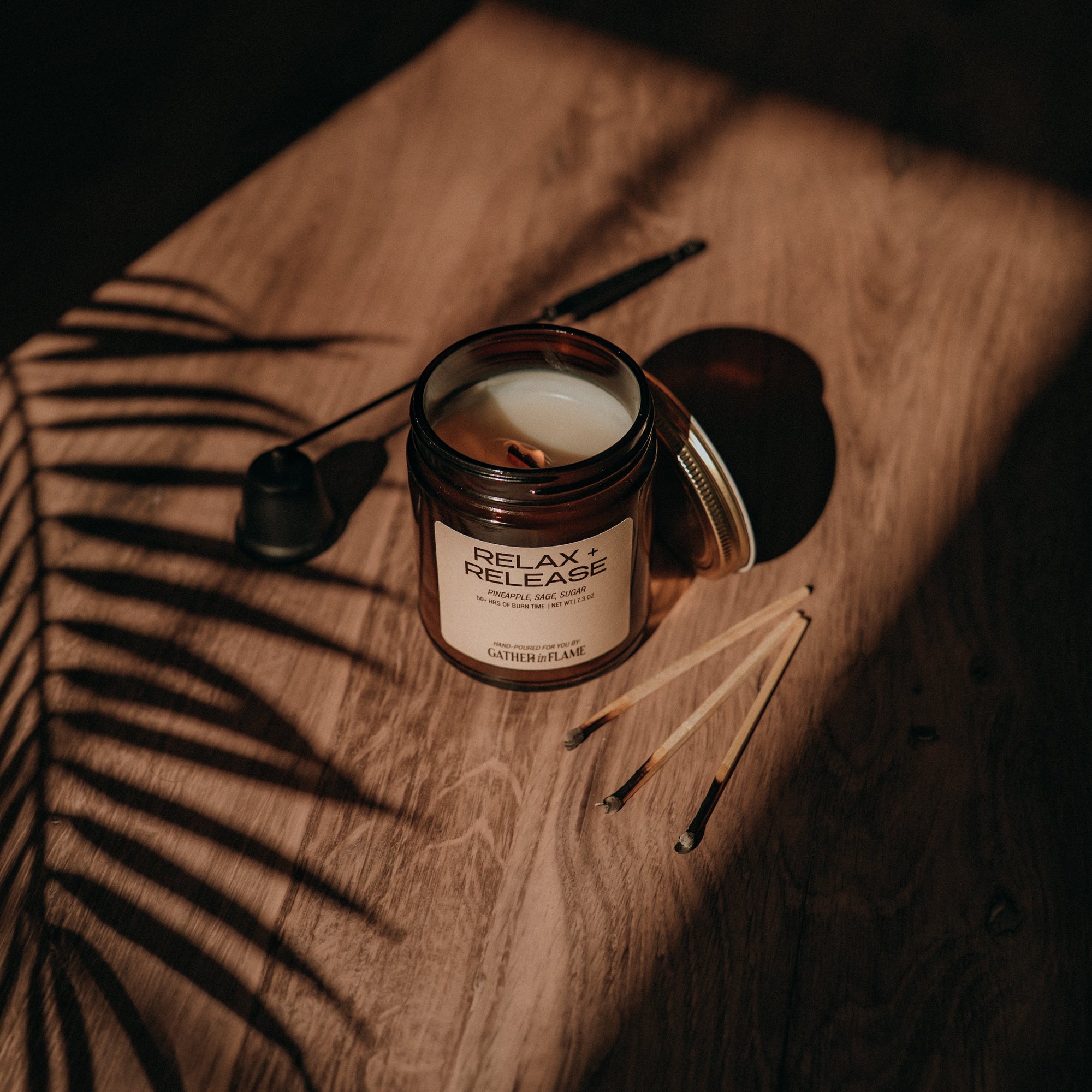 Candle labeled 'Relax Release' on a wooden surface with leaf shadows
