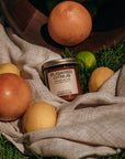Jar of 'Sugared Citrus' on a grassy surface with citrus fruits around