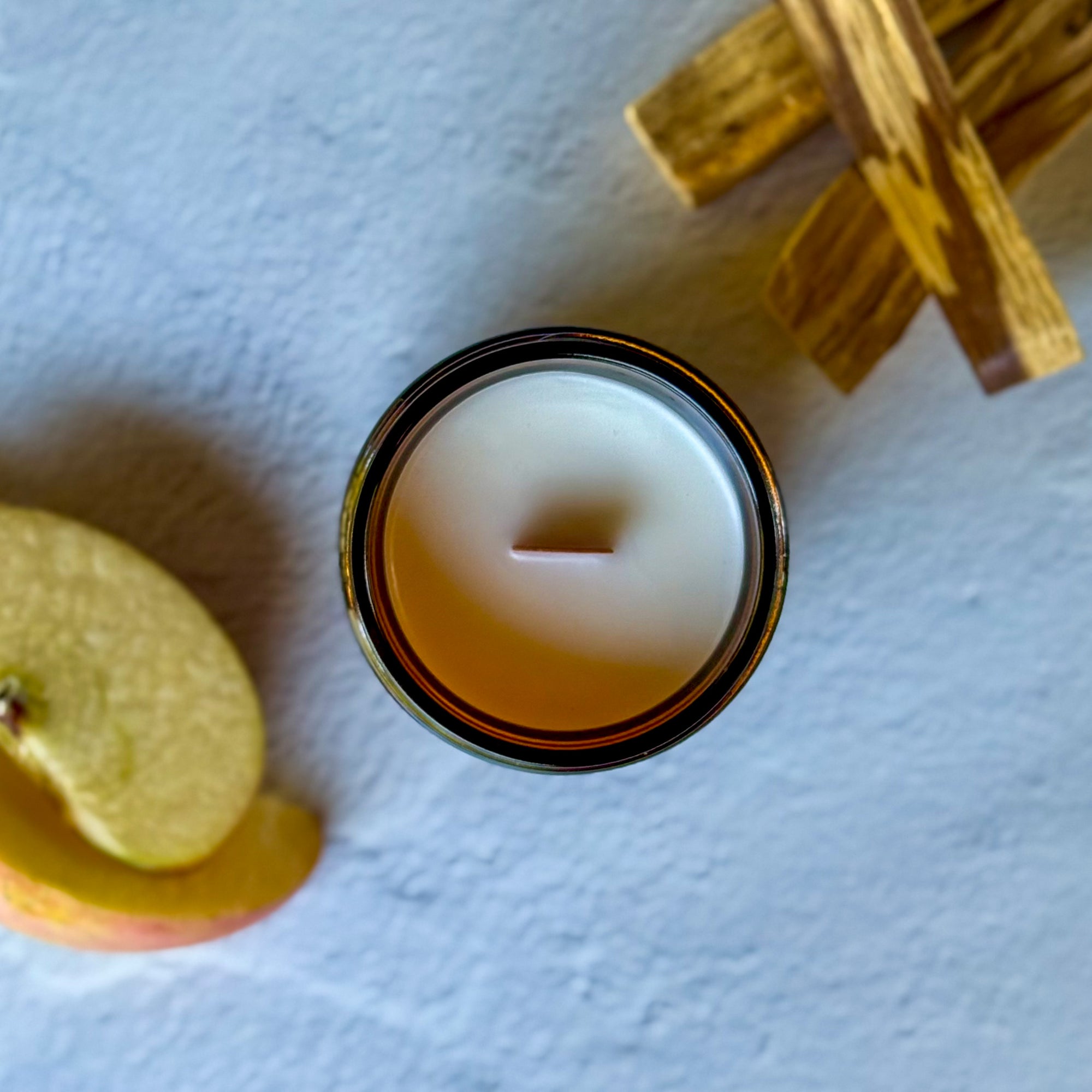 Top down view close-up of a candle with wood wick on a light blue background.