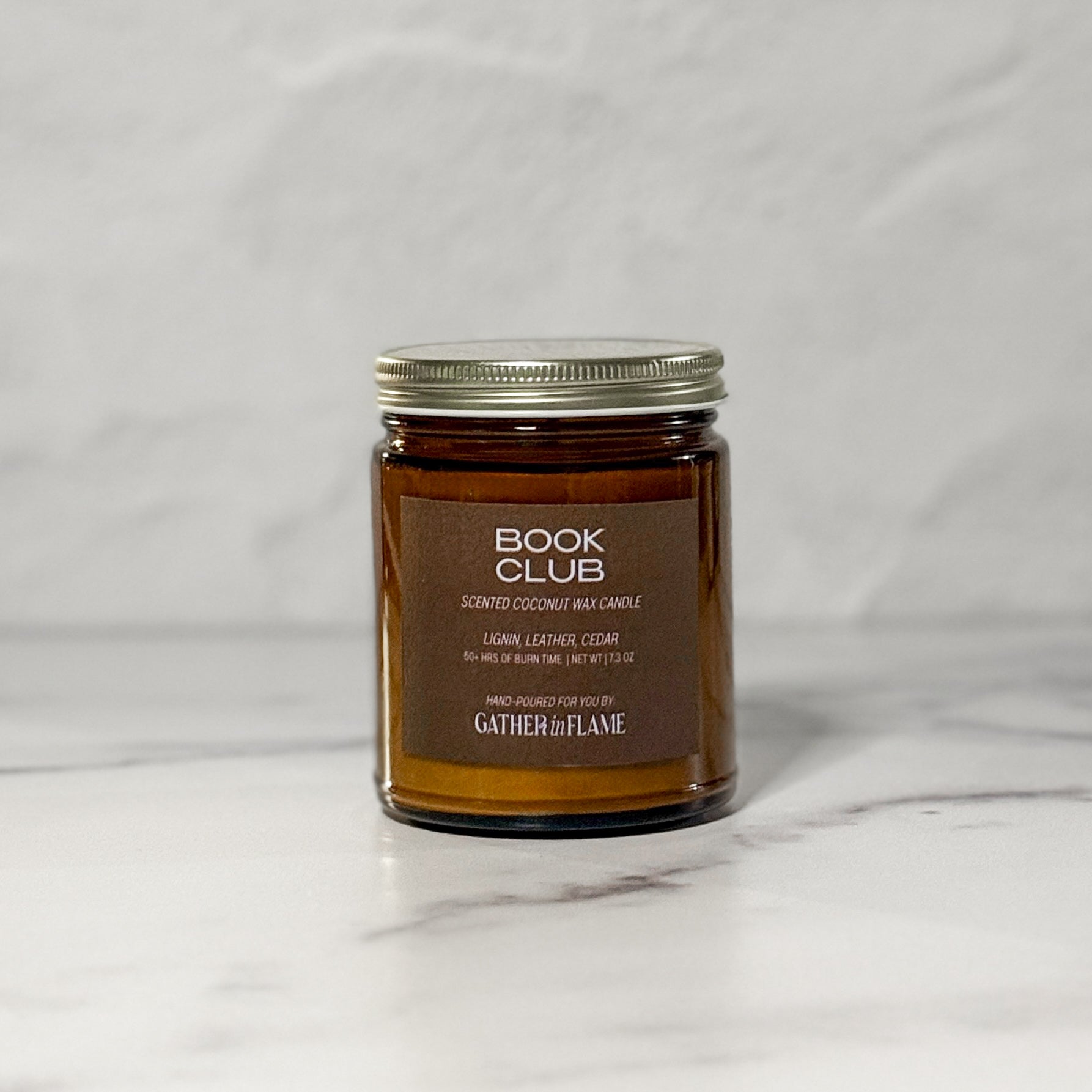 Amber glass jar candle labeled Book Club facing front with a white background.