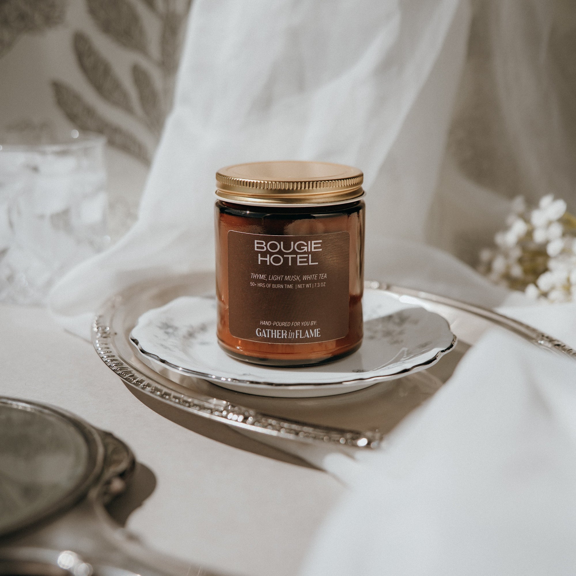 Bougie Hotel candle on a silver tray with white flowers in the background