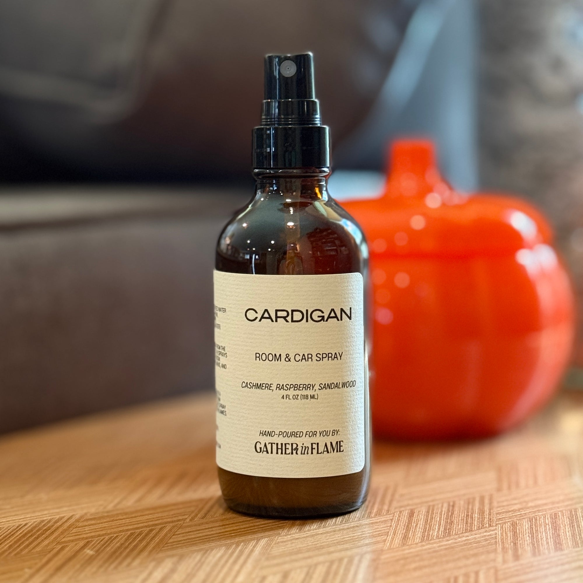 Room and car spray bottle labeled 'Cardigan' on a wooden surface with a blurred background.