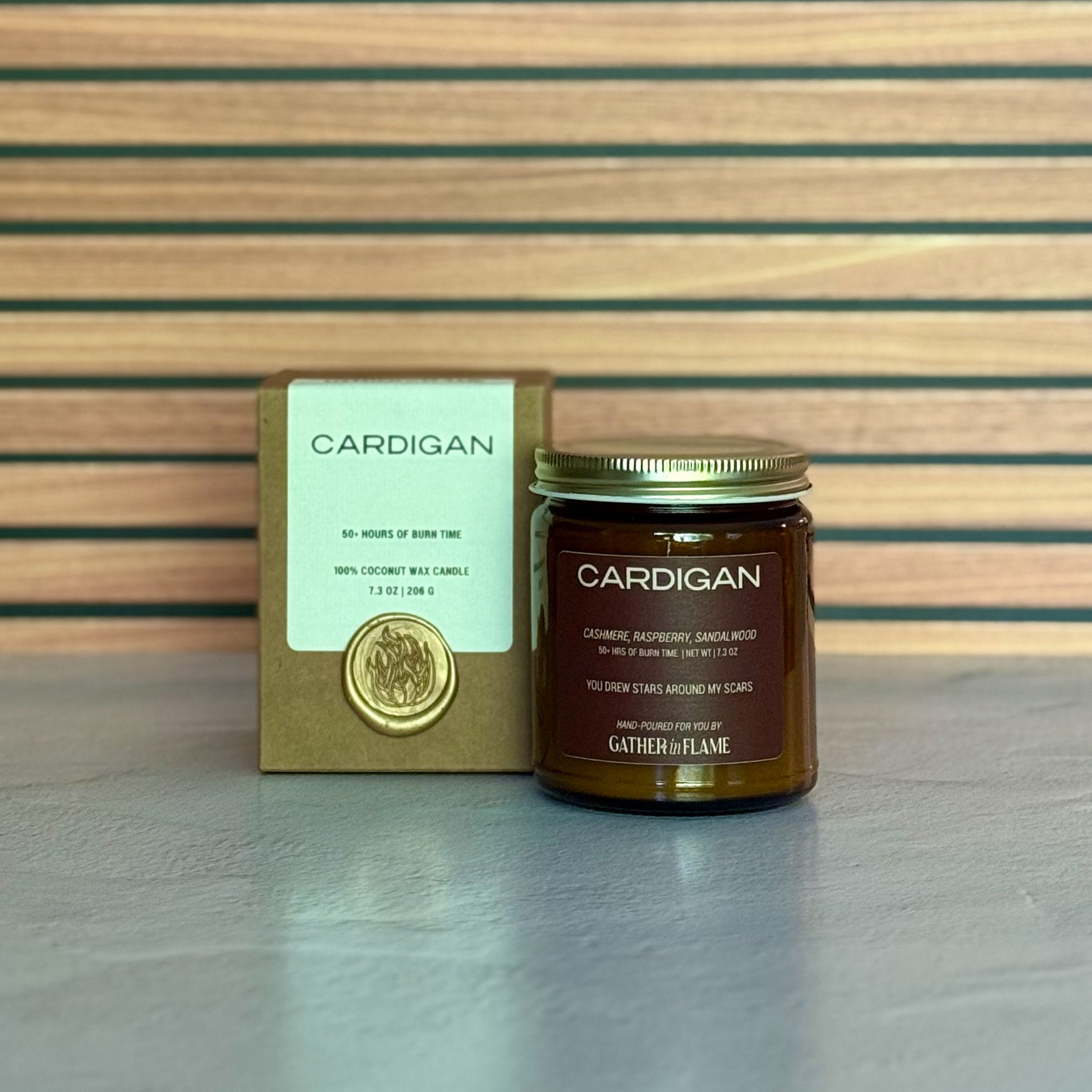 Candle jar labeled 'Cardigan' with packaging on a wooden surface
