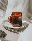 Candle jar labeled 'Champagne Problems' on a decorative tray with a soft background