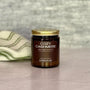 Jar of 'Cozy Cashmere' candle with a gold lid on a neutral background