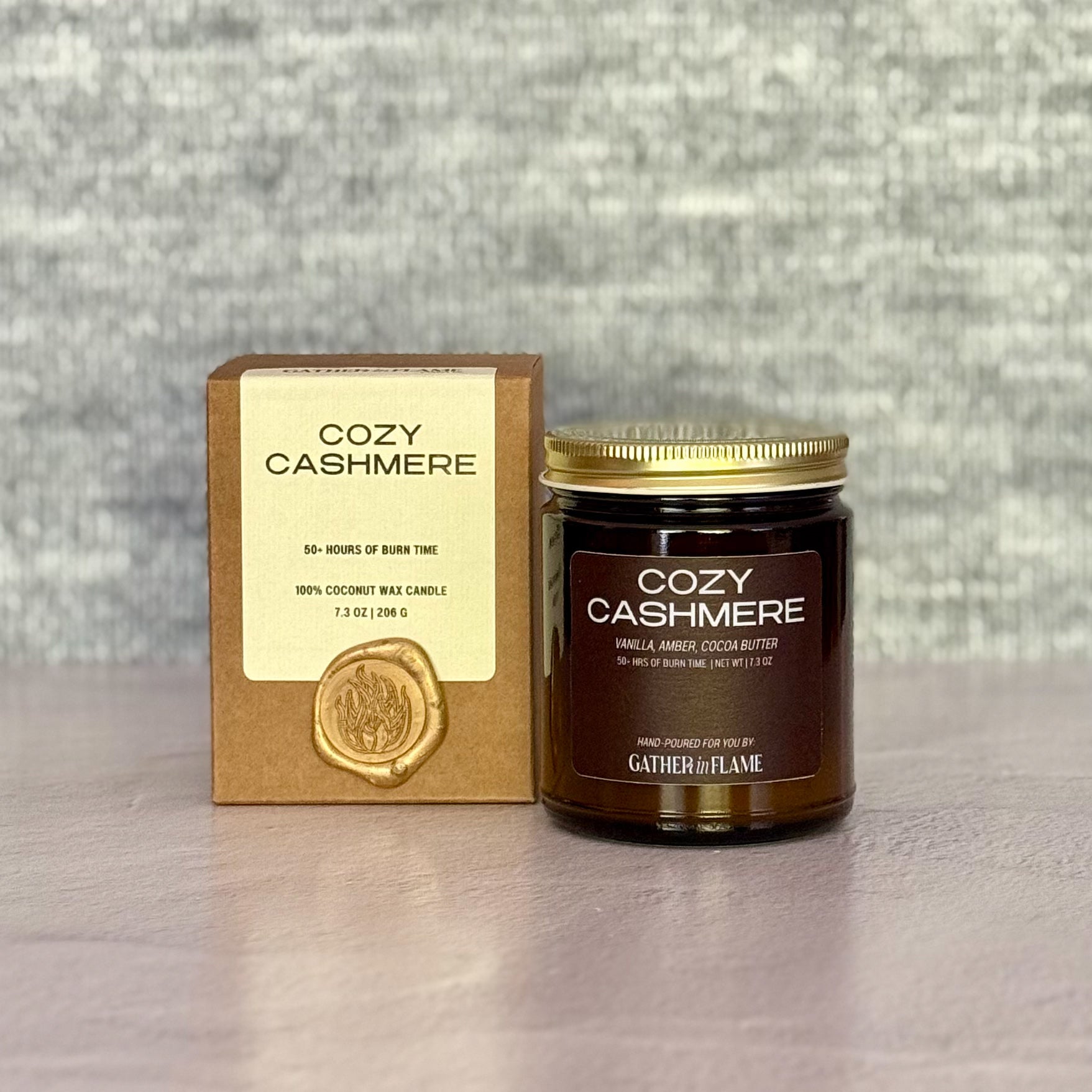Cozy Cashmere candle with packaging on a textured surface