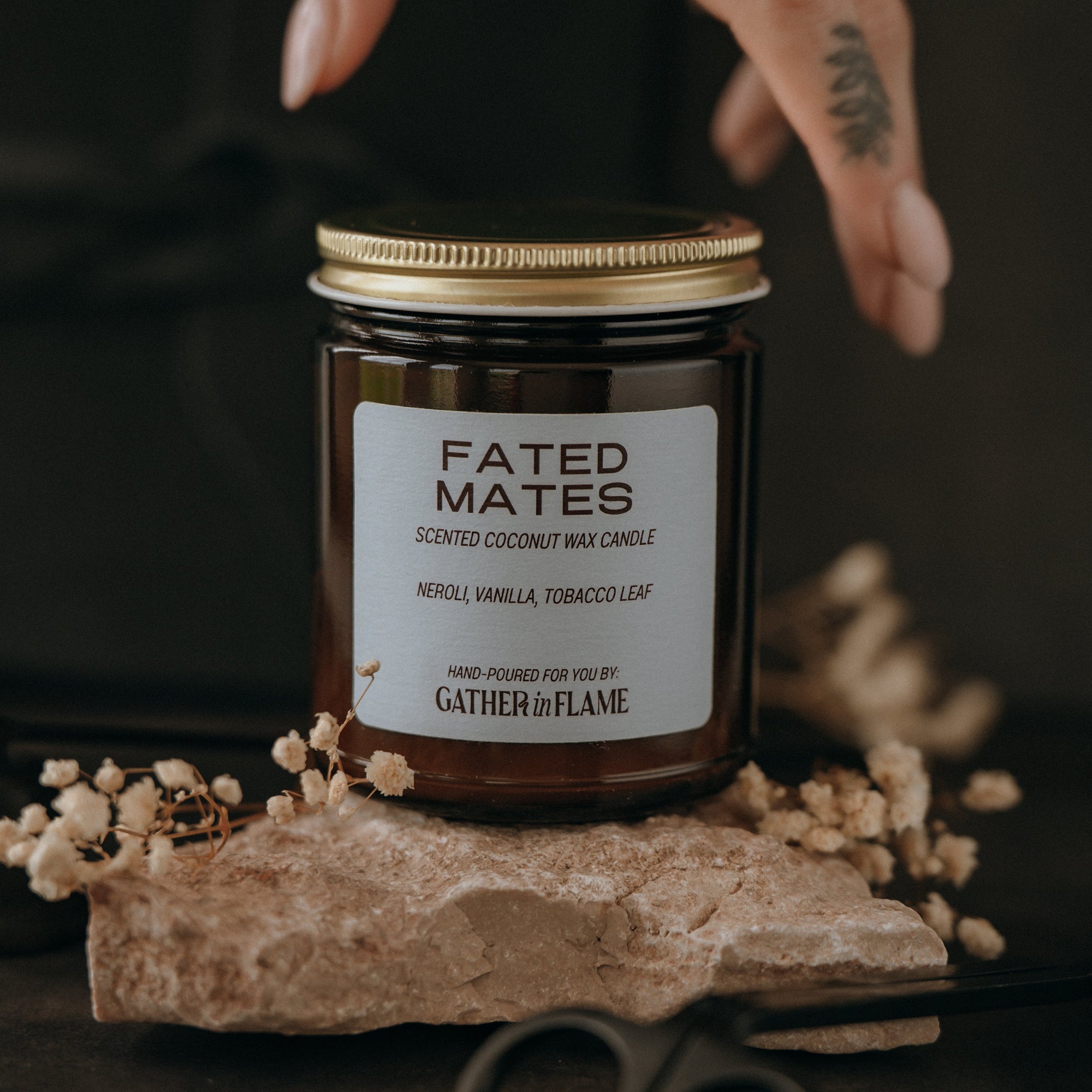 Candle jar labeled 'Fated Mates' with a hand holding it on a dark background