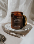 Brown candle jar labeled 'Fresh & Clean' on a white surface with a white curtain background