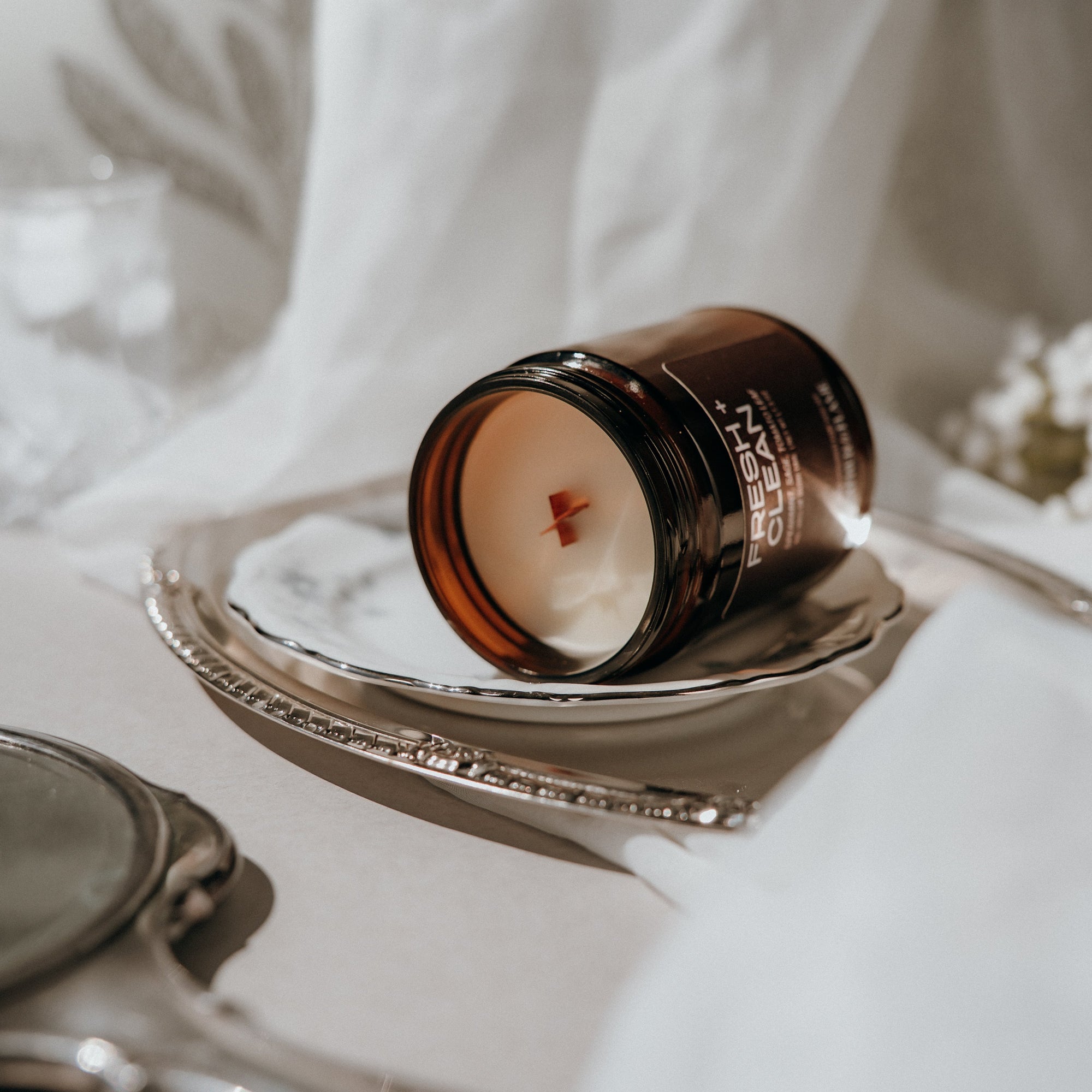 Candle jar in a decorative holder on a white surface