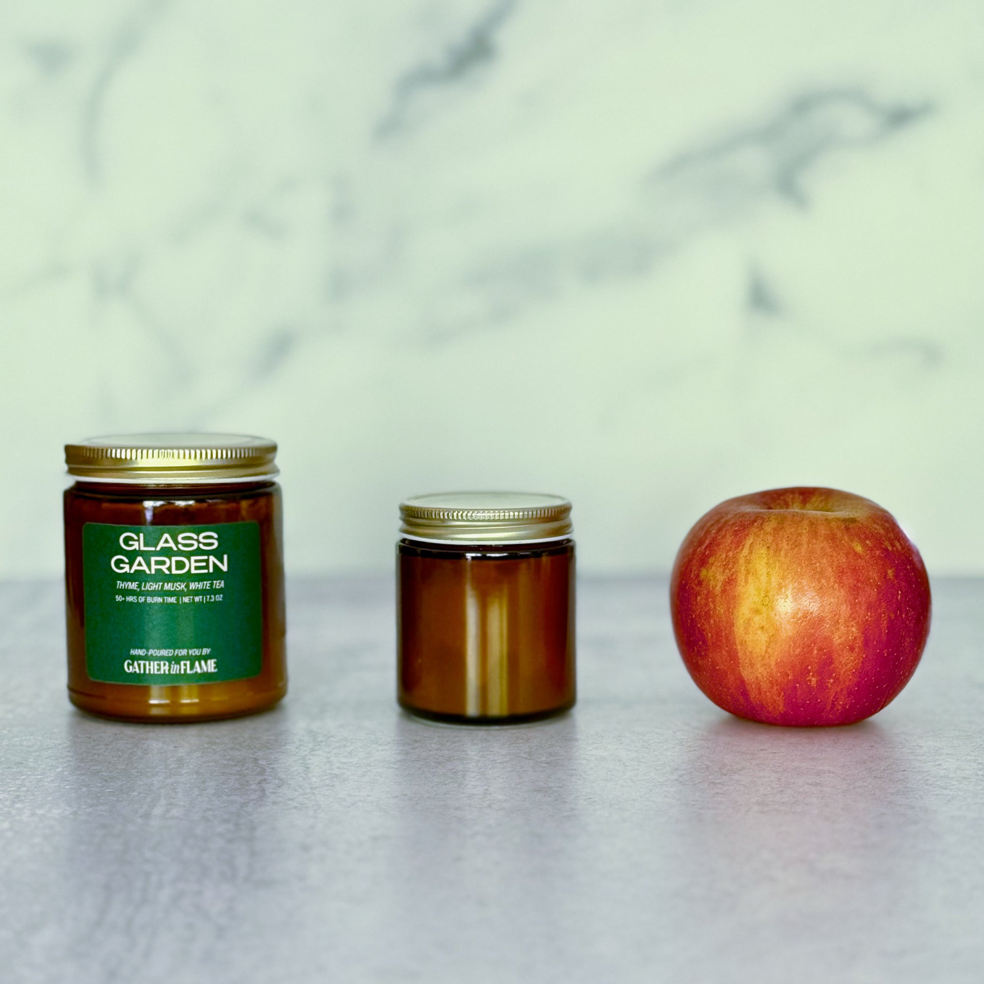 Two jars and an apple on a marble surface