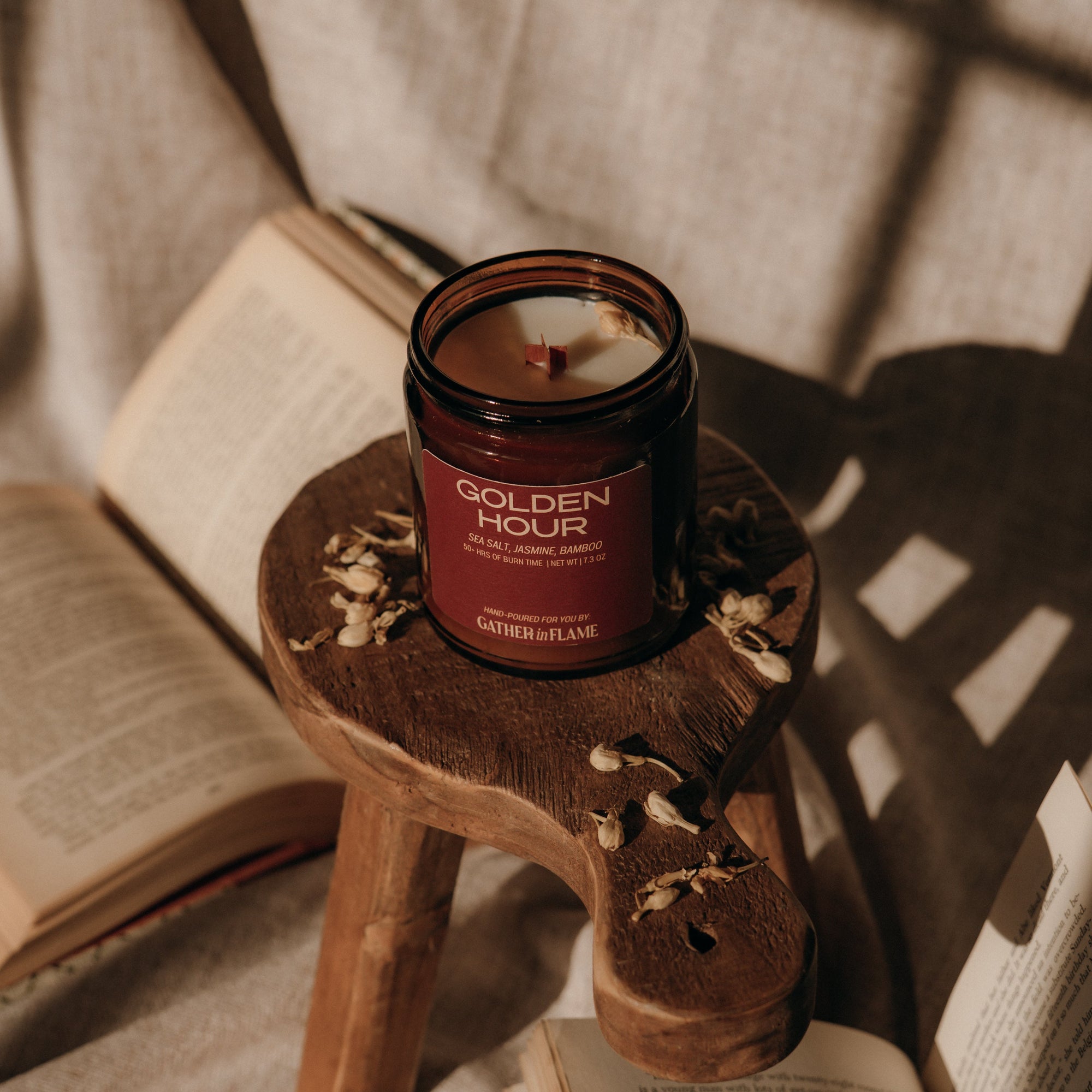 Candle labeled 'Golden Hour' on a small wooden stool with books in the background