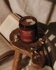 Candle labeled 'Golden Hour' on a small wooden stool with books in the background