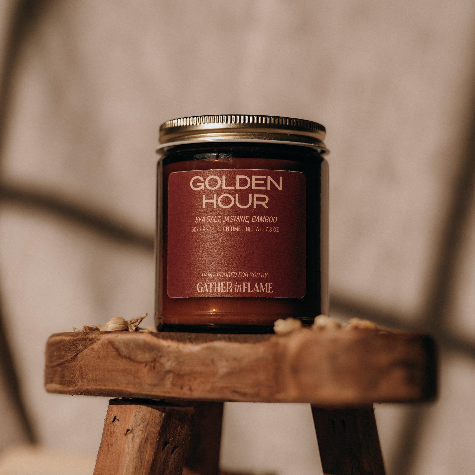 Candle jar labeled 'Golden Hour' on a wooden stand with a blurred background