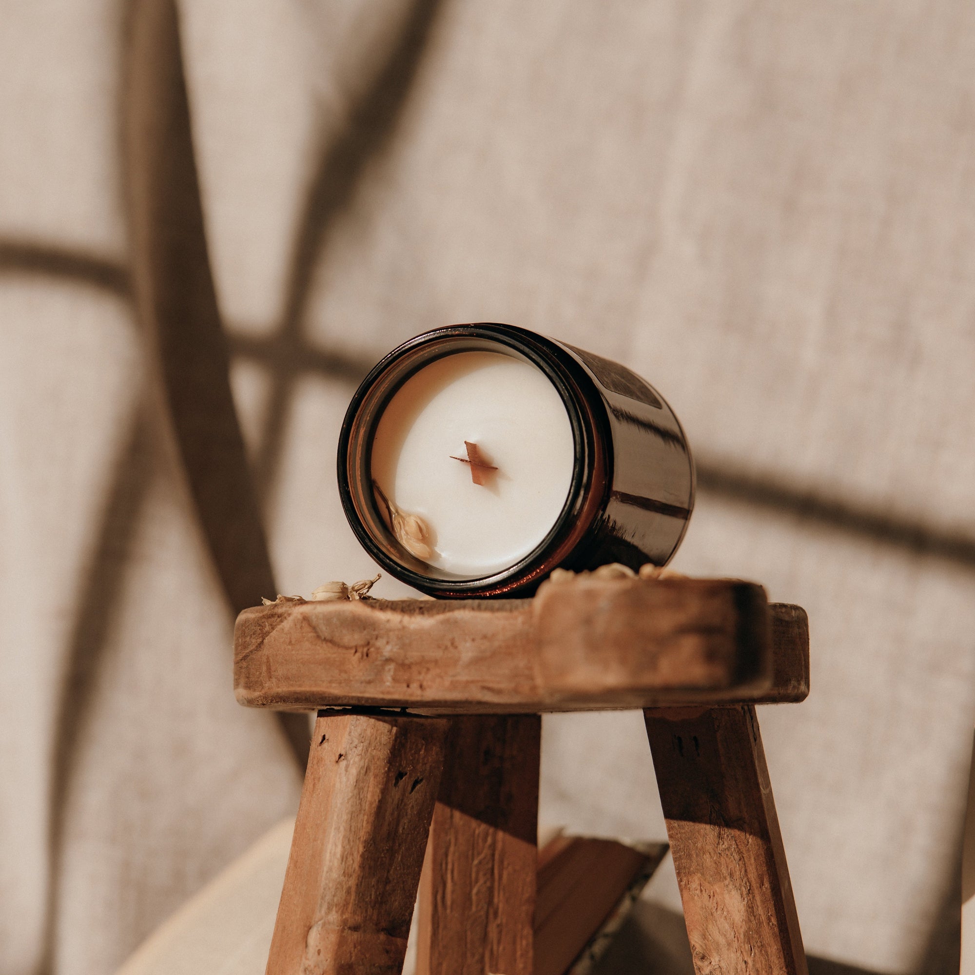 Candle in a wooden holder on a textured surface with soft lighting
