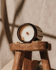 Candle in a wooden holder on a textured surface with soft lighting