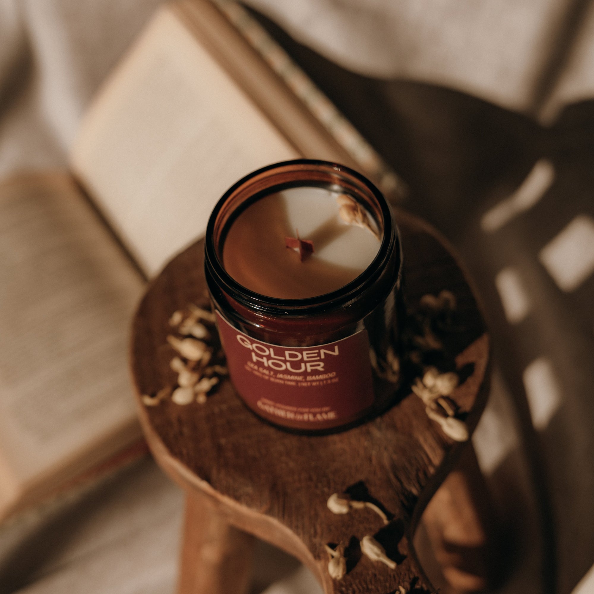 Candle in a decorative jar on a wooden stand with a neutral background