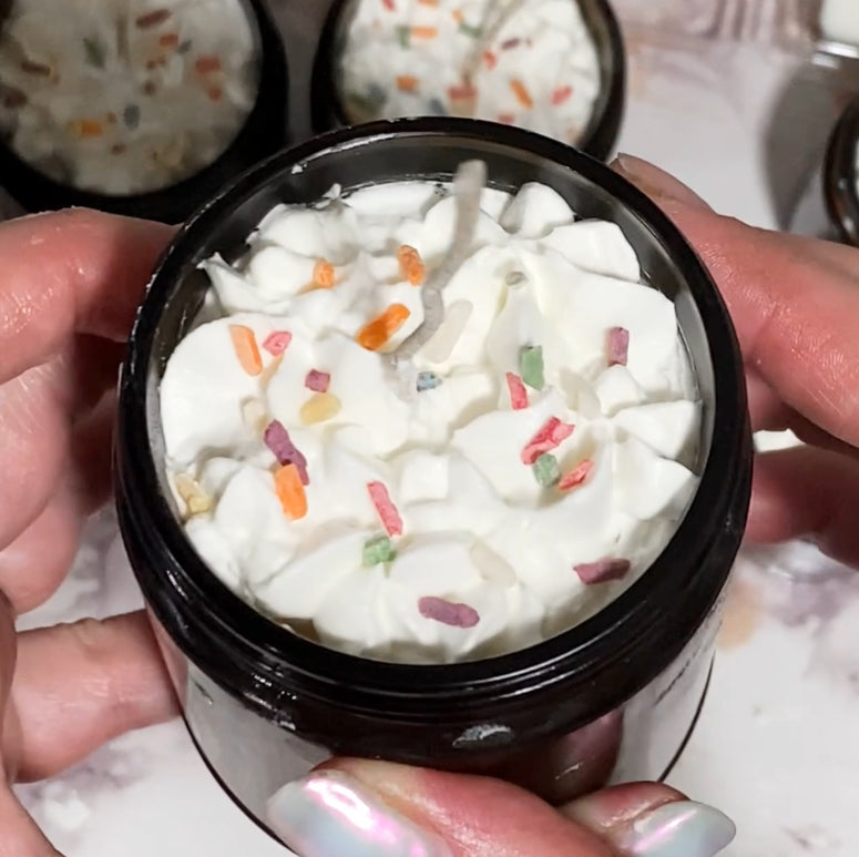 A jar candle with surface that looks like whipped frosting with rainbow wax sprinkles.