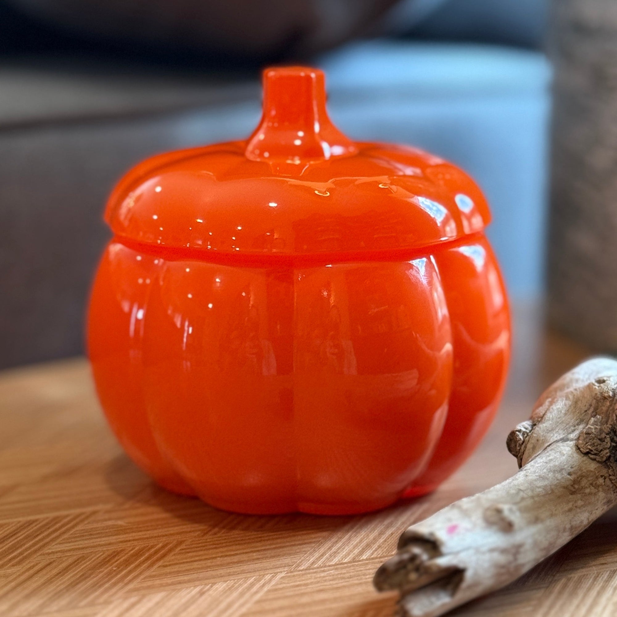 Orange pumpkin-shaped container on a wooden surface with a blurred background