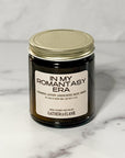 Close up of amber glass jar candle labeled In My Romantasy Era with a white background.