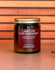 Jar of 'Last of the Harvest' candle with a wooden wick on a striped background