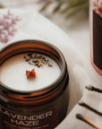 Candle jar labeled 'Lavender Haze' with lavender flowers and matches in the background