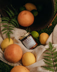Jar of Manuka Honey surrounded by fruits on a natural fabric with greenery