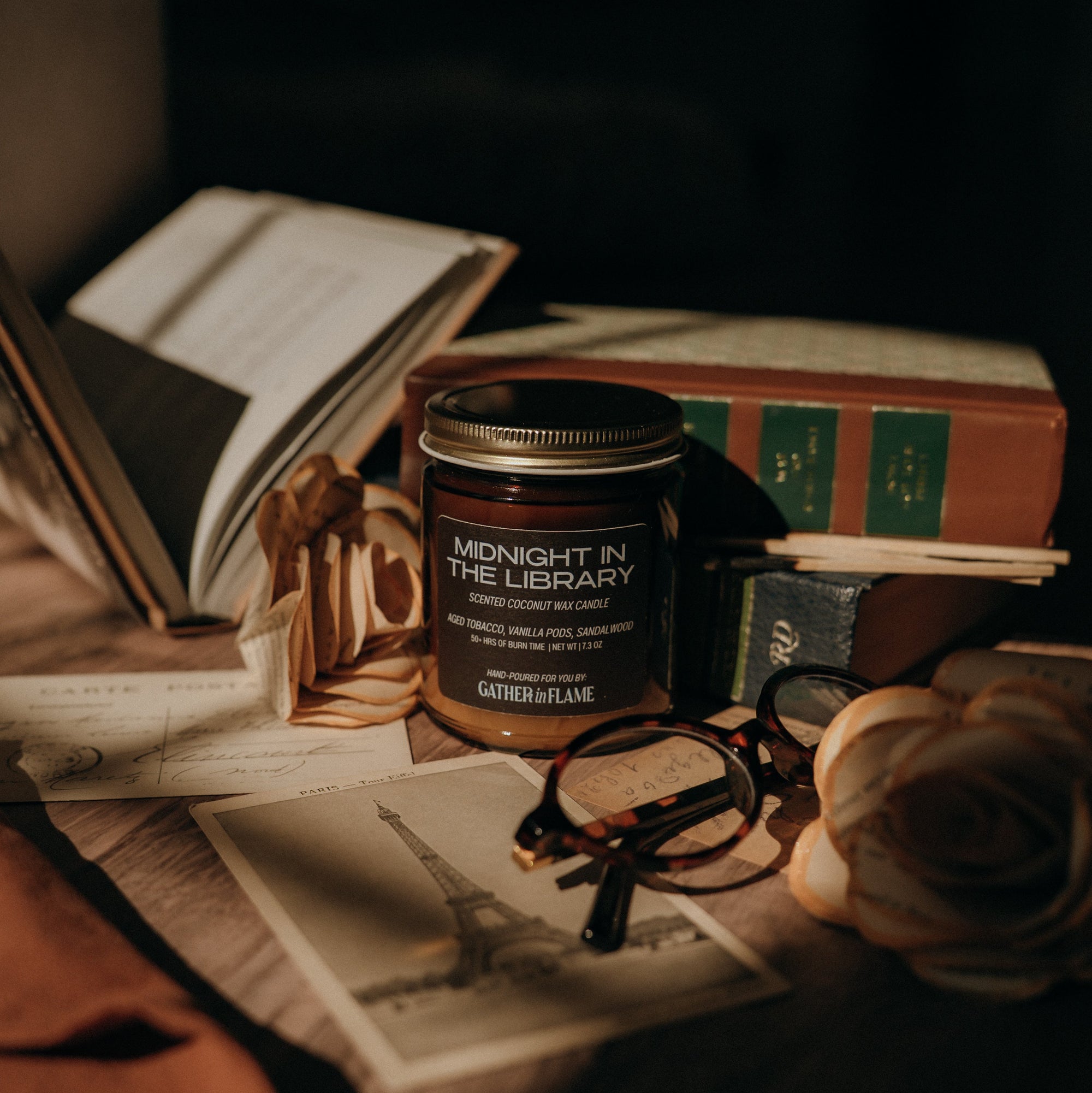 Candle labeled 'Midnight in the Library' on books with a dark background
