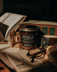 Candle labeled 'Midnight in the Library' on books with a dark background