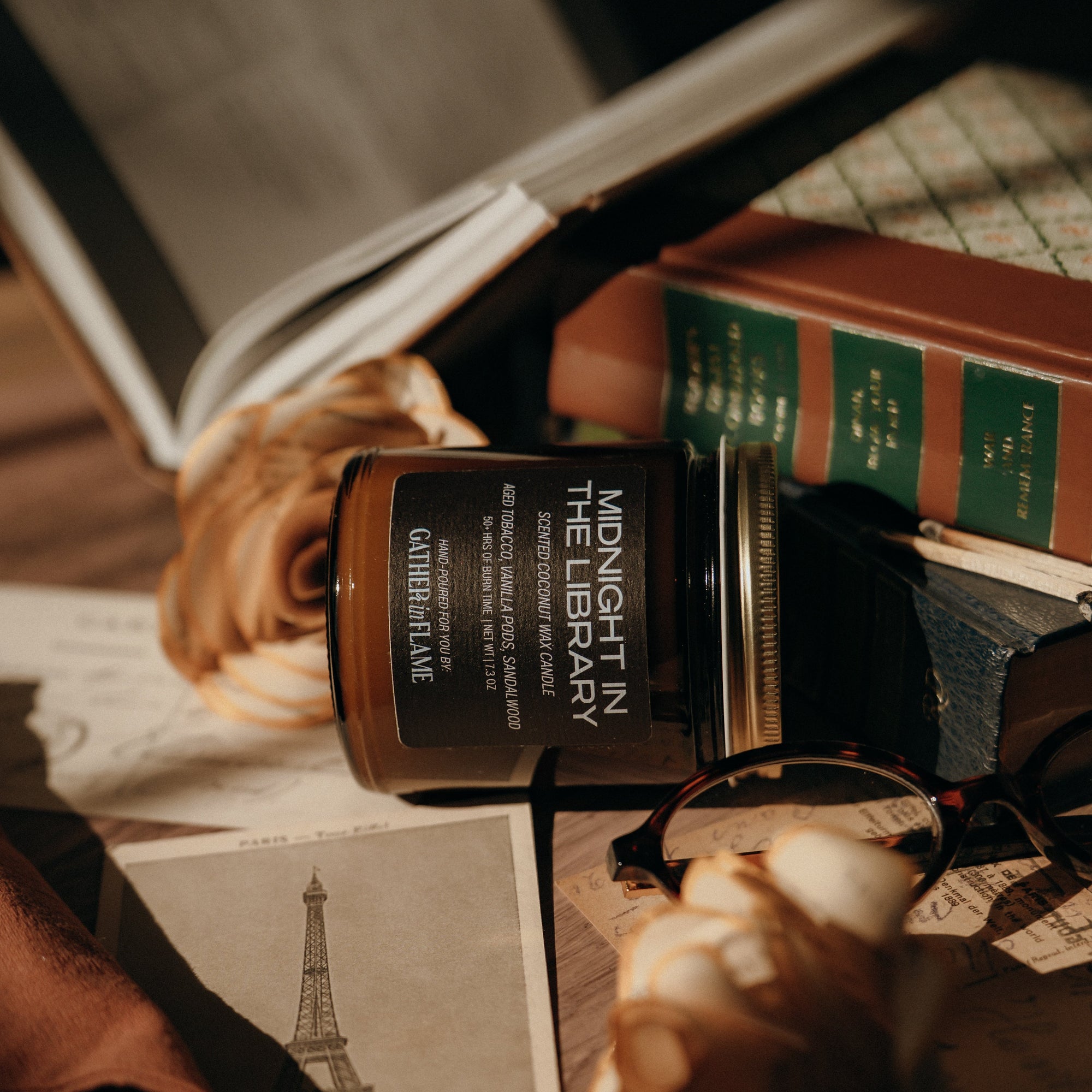 Book with a  'Midnight in the Library' candle on top, surrounded by roses and a photo of the Eiffel Tower.