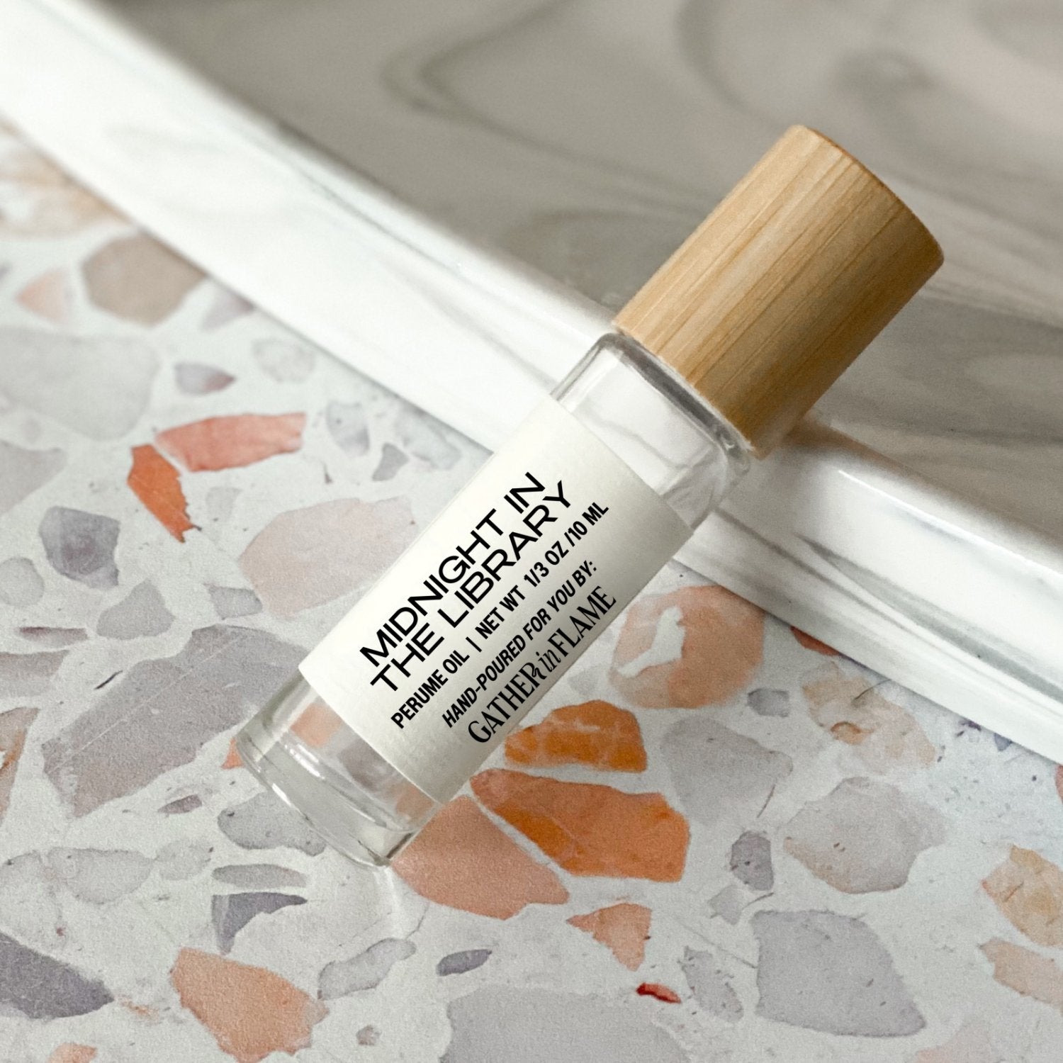 perfume roller labeled Midnight in the Library on a terrazzo surface