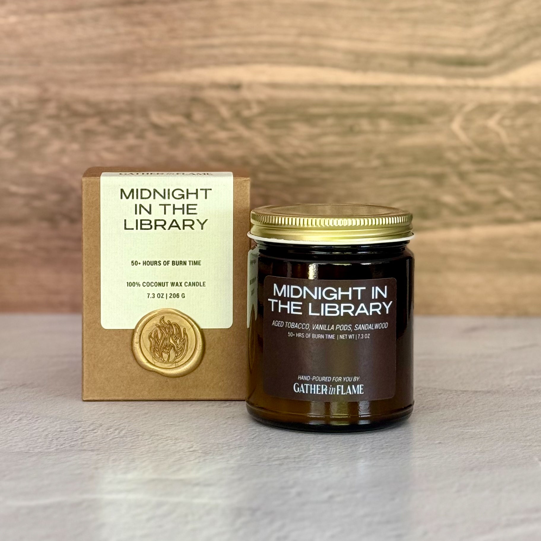 Candle labeled 'Midnight in the Library' with packaging on a wooden surface