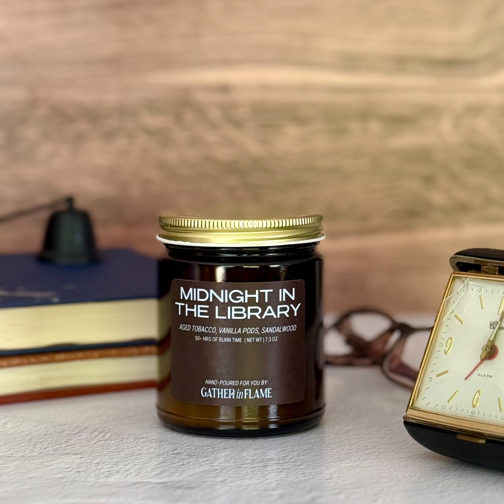 Candle jar labeled 'Midnight in the Library' with a clock and books in the background