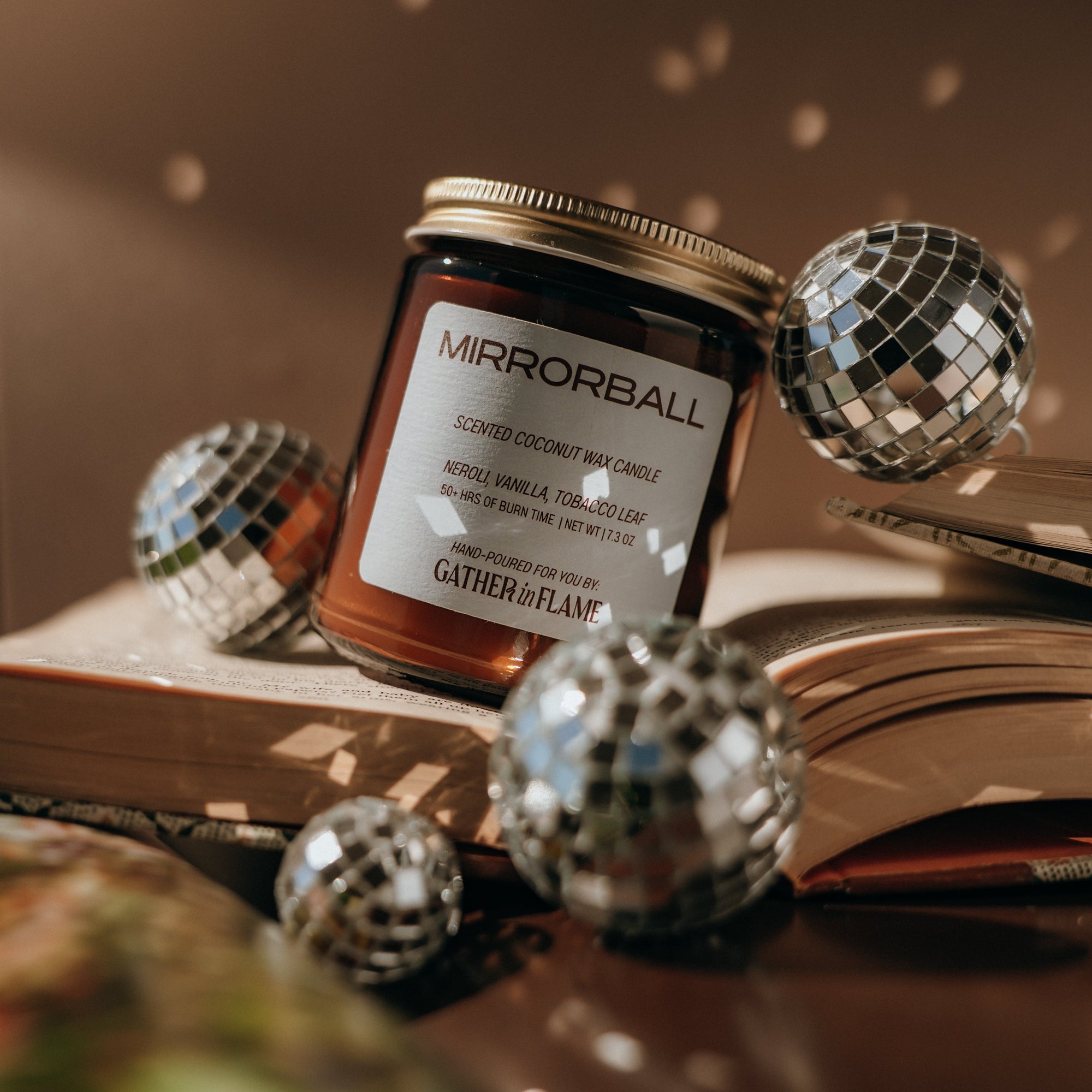 Jar of 'Mirrorball' candle with disco balls on an open book