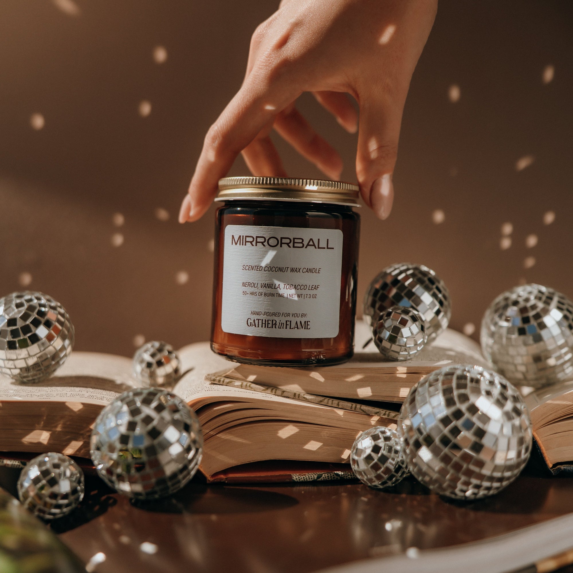 Hand reaching for a jar labeled 'Mirrorball' surrounded by disco balls on an open book.