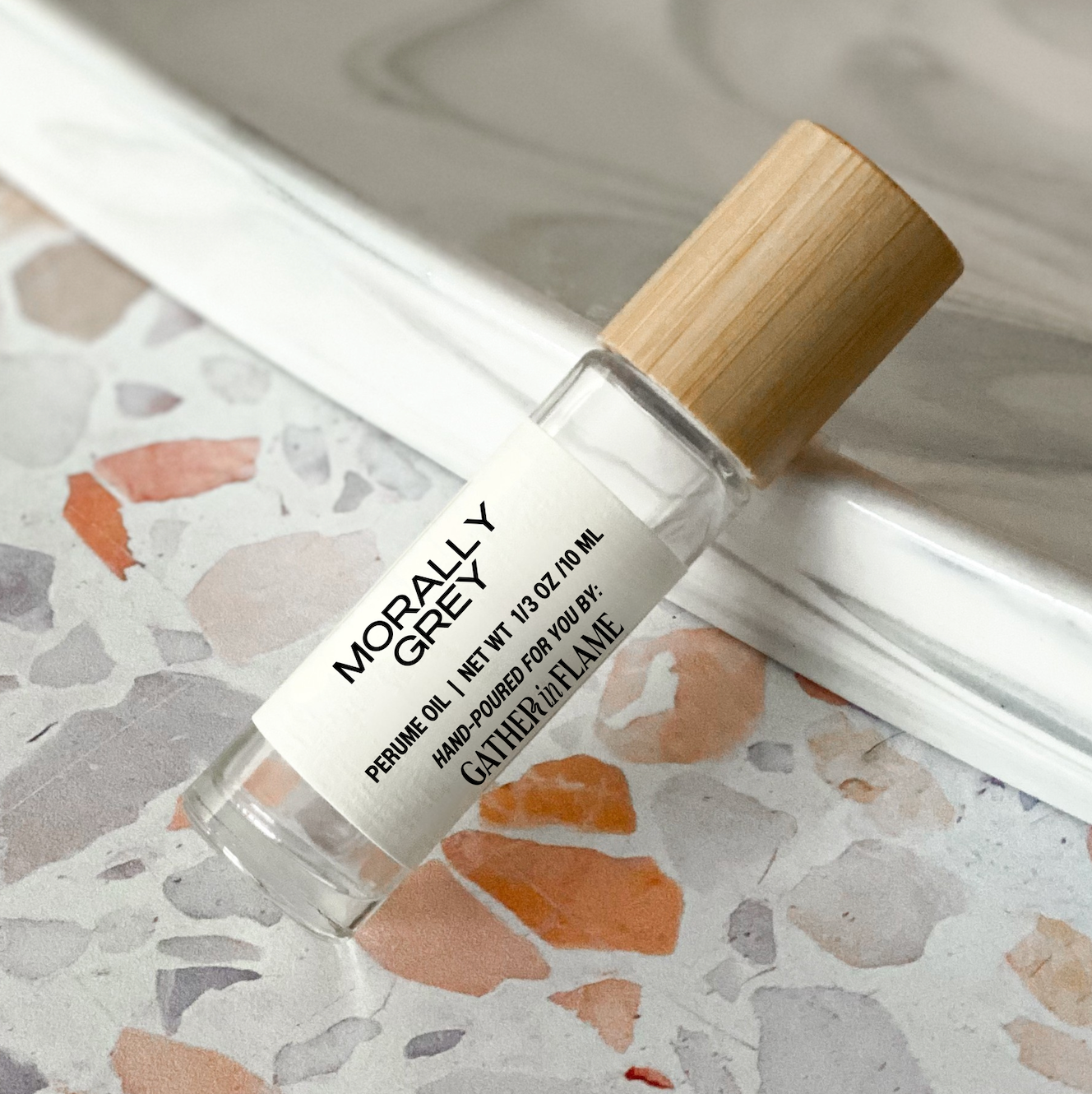 Perfume oil bottle labeled 'Morally Grey' on a terrazzo surface