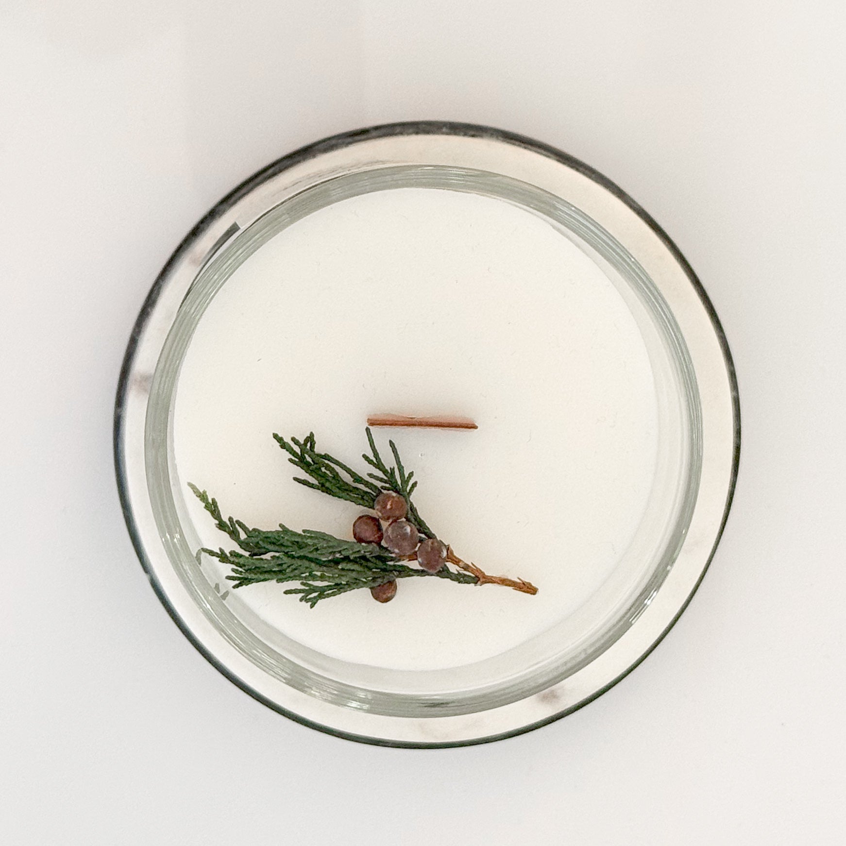 Overhead view of 12oz Oregon Evergreen candle with wood wick and juniper sprig on surface