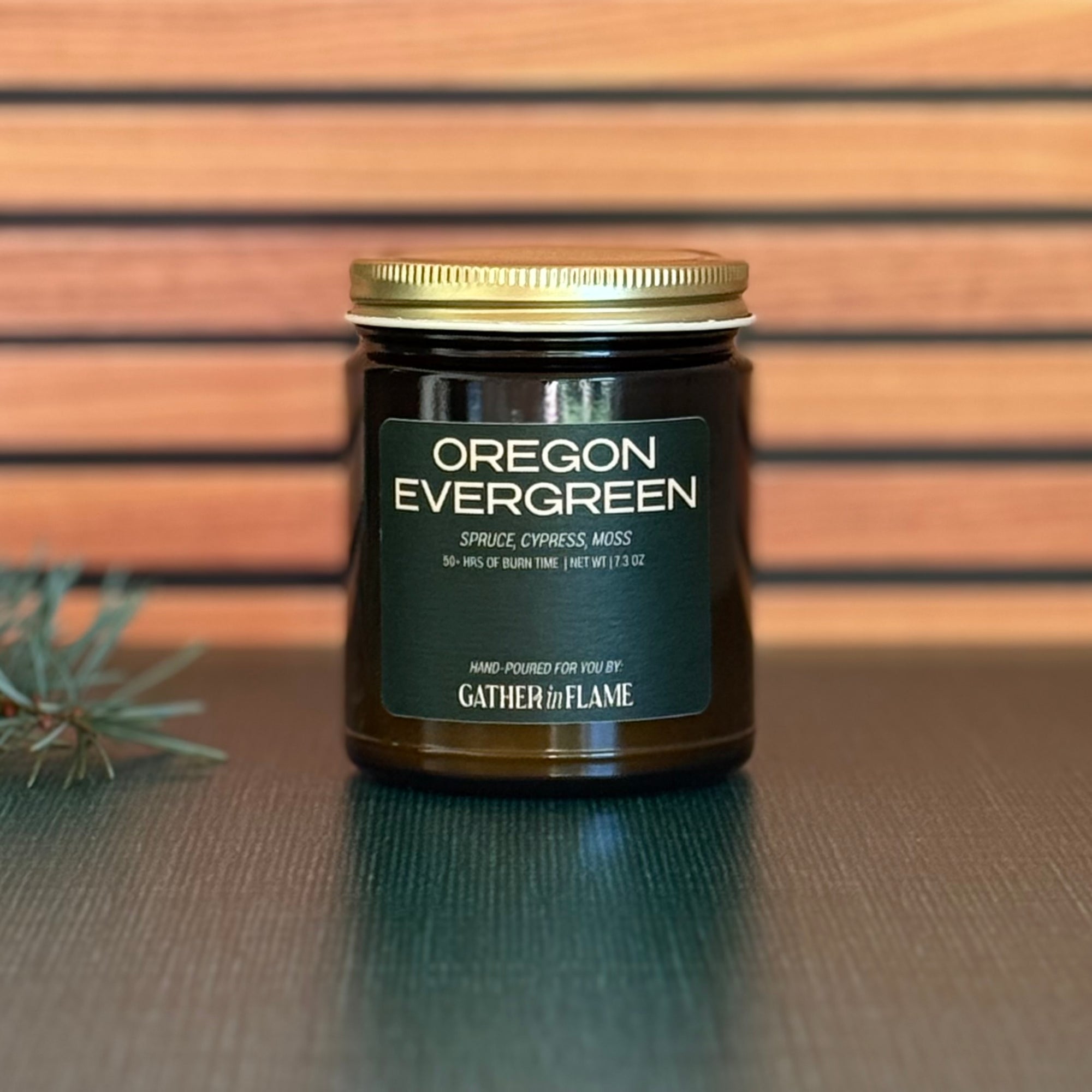 Jar of 'Oregon Evergreen' candle with a gold lid on a wooden surface