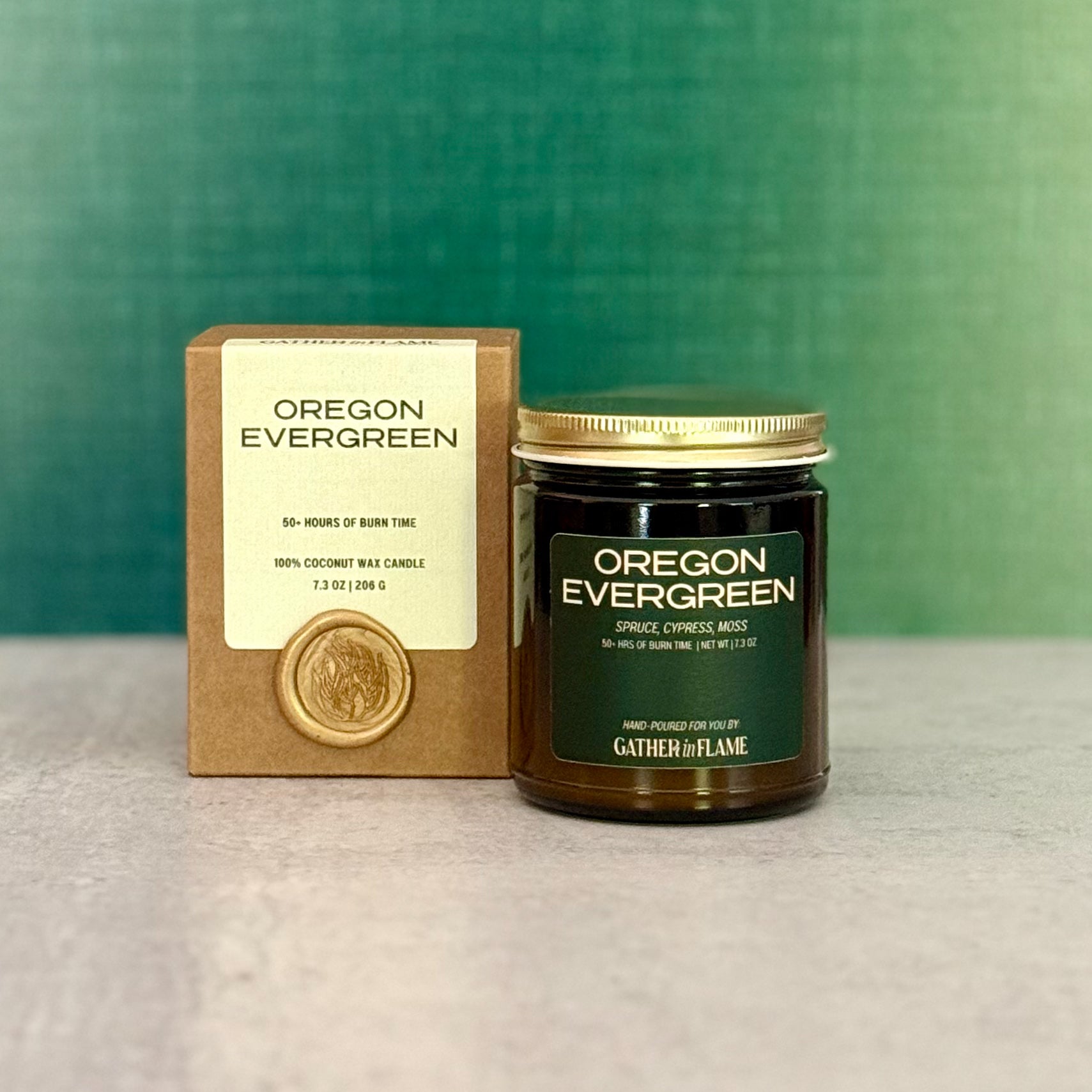  'Oregon Evergreen' candle with packaging and wax seal on a grey surface with green background