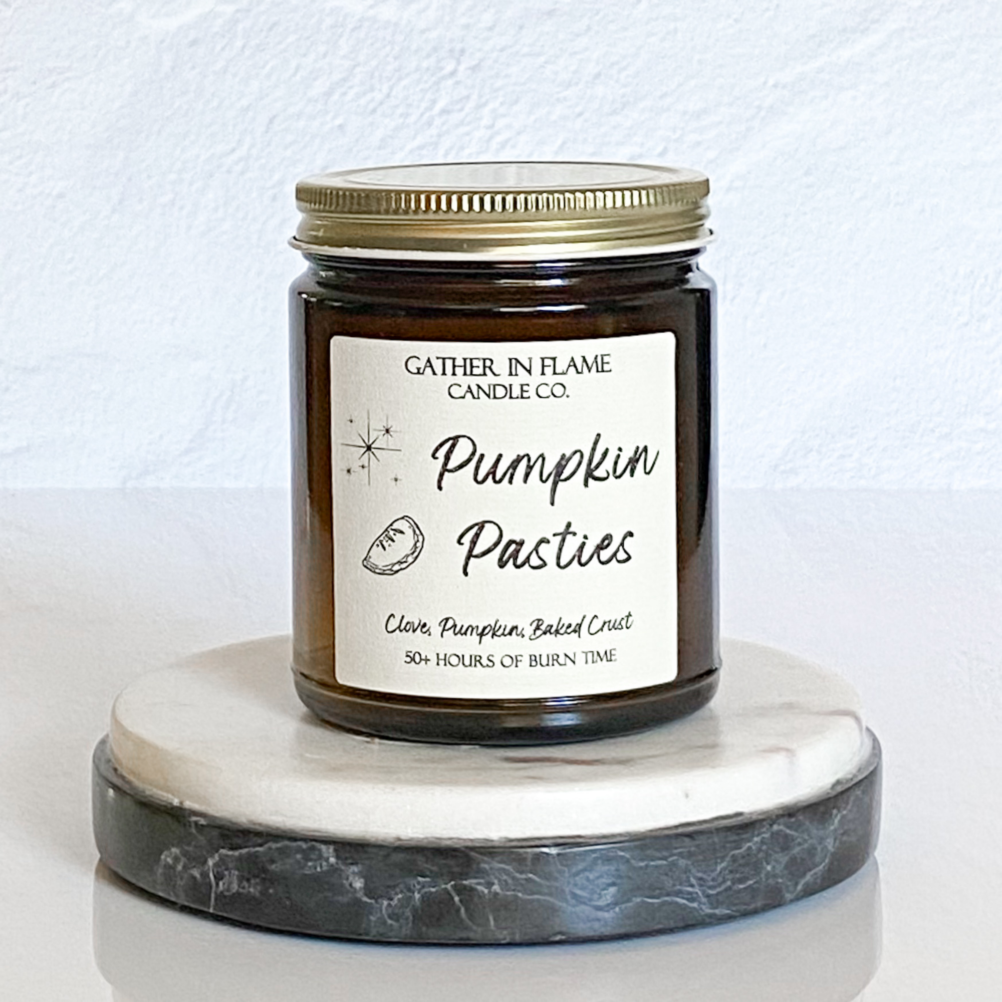 A jar candle with a label reading 'Pumpkin Pasties' on a marble-like surface.